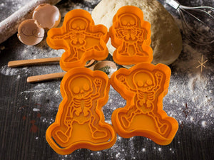 Halloween skeleton cookie cutters in four spooky designs on a baking table with flour and eggs.