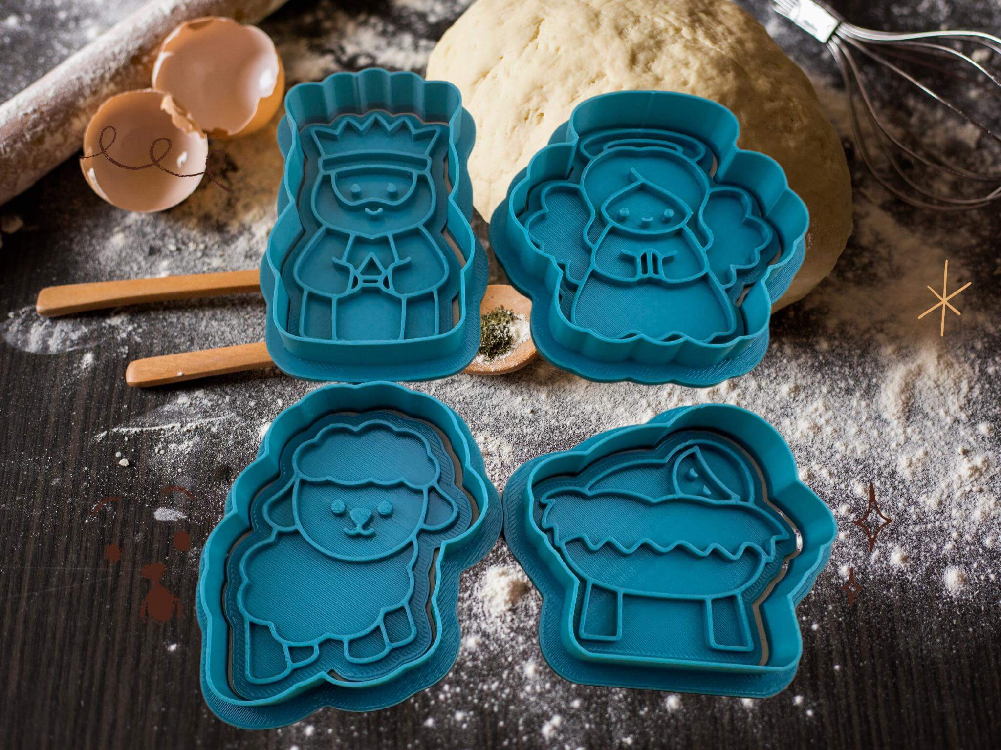 Weihnachtliche Keks-Ausstecher in Form von Engel, König, Schaf und Jesuskind auf einer Backfläche.