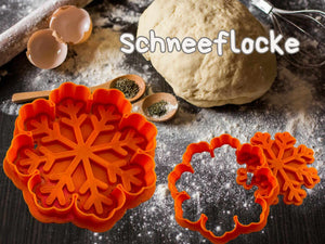 Orange Schneeflocken-Ausstecher auf einer Küchentheke mit Teig und Backzubehör für festliche Kekse.