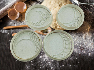 Set of four mystical moon phase cookie cutters on a flour-dusted kitchen counter, perfect for baking and themed parties.