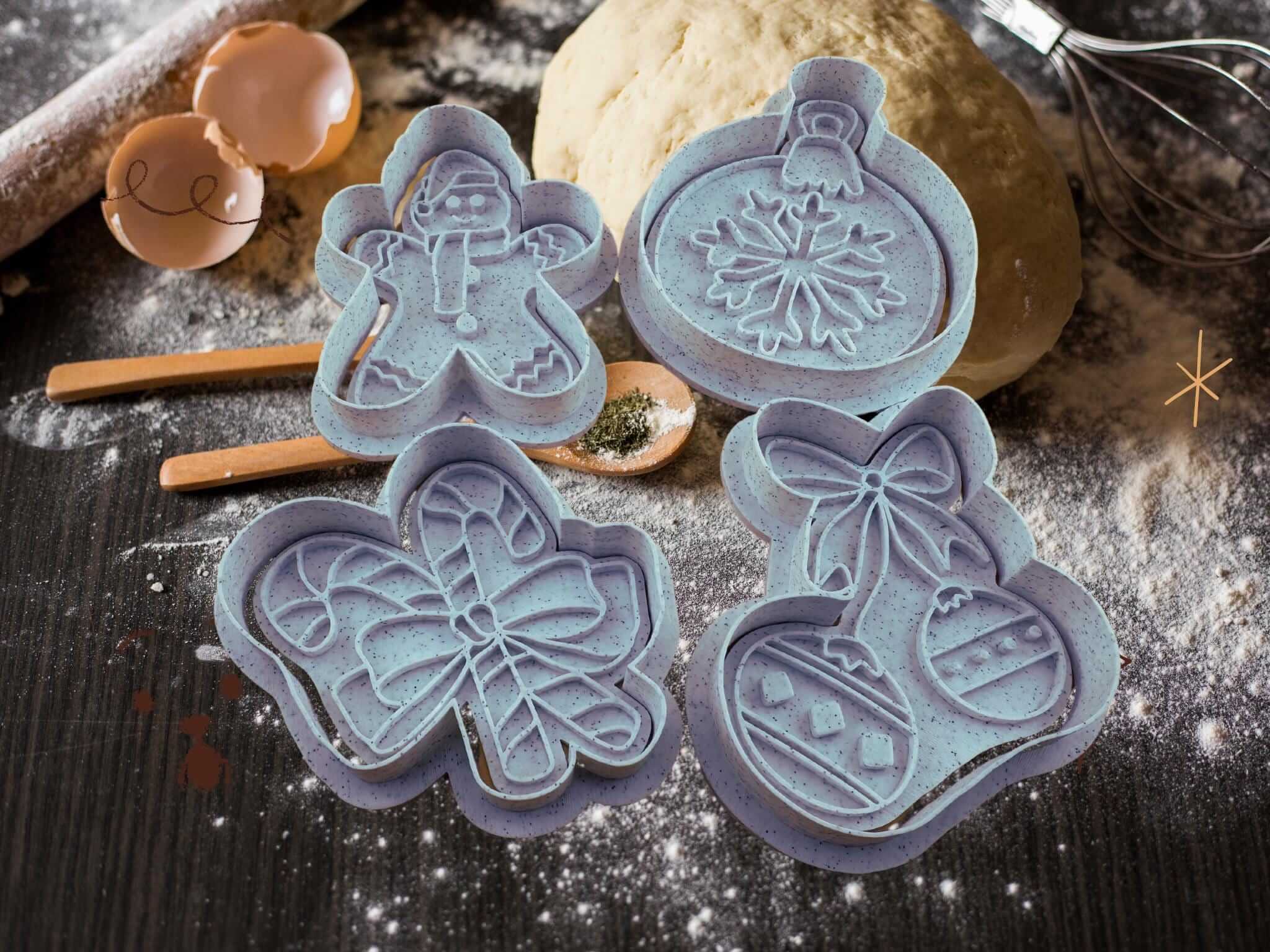 Weihnachtliche Keks-Ausstecher in verschiedenen festlichen Formen: Lebkuchenmann, Kugel, Zuckerstange und Weihnachtsornament.