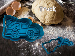 Blue truck-shaped cookie cutter beside dough, ideal for festive baking. Features a Christmas tree on the truck. Perfect for holiday cookies.