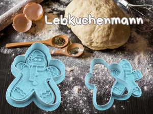 Lebkuchenmann Keks-Ausstecher auf einer Küchentheke mit Teig und Zutaten für Weihnachtsplätzchen.