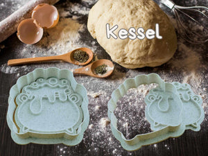 Halloween Keks-Ausstecher in Kessel-Form mit Brotteig auf bemehltem Tisch, perfektes Backzubehör für gruselige Kekse.