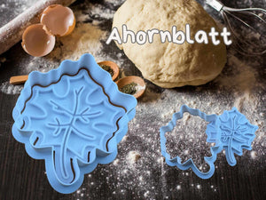 Keksausstecher in Herbstblatt-Form auf einer bemehlten Arbeitsfläche mit Teig und Eierschalen.