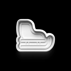 White sled-shaped cookie cutter on a black background, perfect for winter-themed baking and creative cookies.