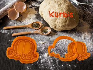 Kürbis Keks-Ausstecher auf der Arbeitsfläche mit Teig und Gewürzen, perfekt für herbstliches Backen.