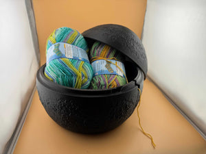 Praktische Garnschale mit bunten Wollknäueln, ideal für Strick- und Häkelprojekte, zeigt Fadenausgang.