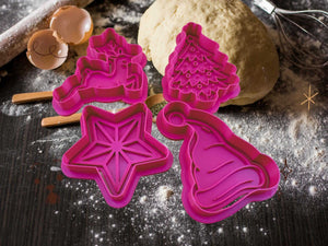 Weihnachtliche Keks-Ausstecher in Pink: Rentier, Baum, Stern und Mütze auf einem Holztisch mit Teig.