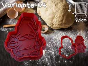 Roten Keks-Ausstecher mit lustigem Wichtel-Motiv und Teig auf einem schwarzen Tisch, ideal für kreative Weihnachtsbäckerei.