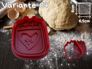 Valentinstag Herz Ausstechform für Kekse, rote Kunststoffform mit Herz-Design, neben Teig und Mehl auf einer Backunterlage.