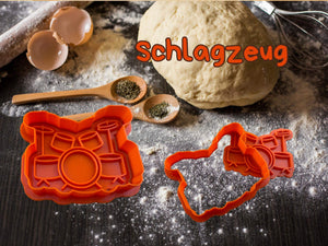 Musik Keks-Ausstecher für Schlagzeug in leuchtendem Orange auf einer bemehlten Oberfläche.