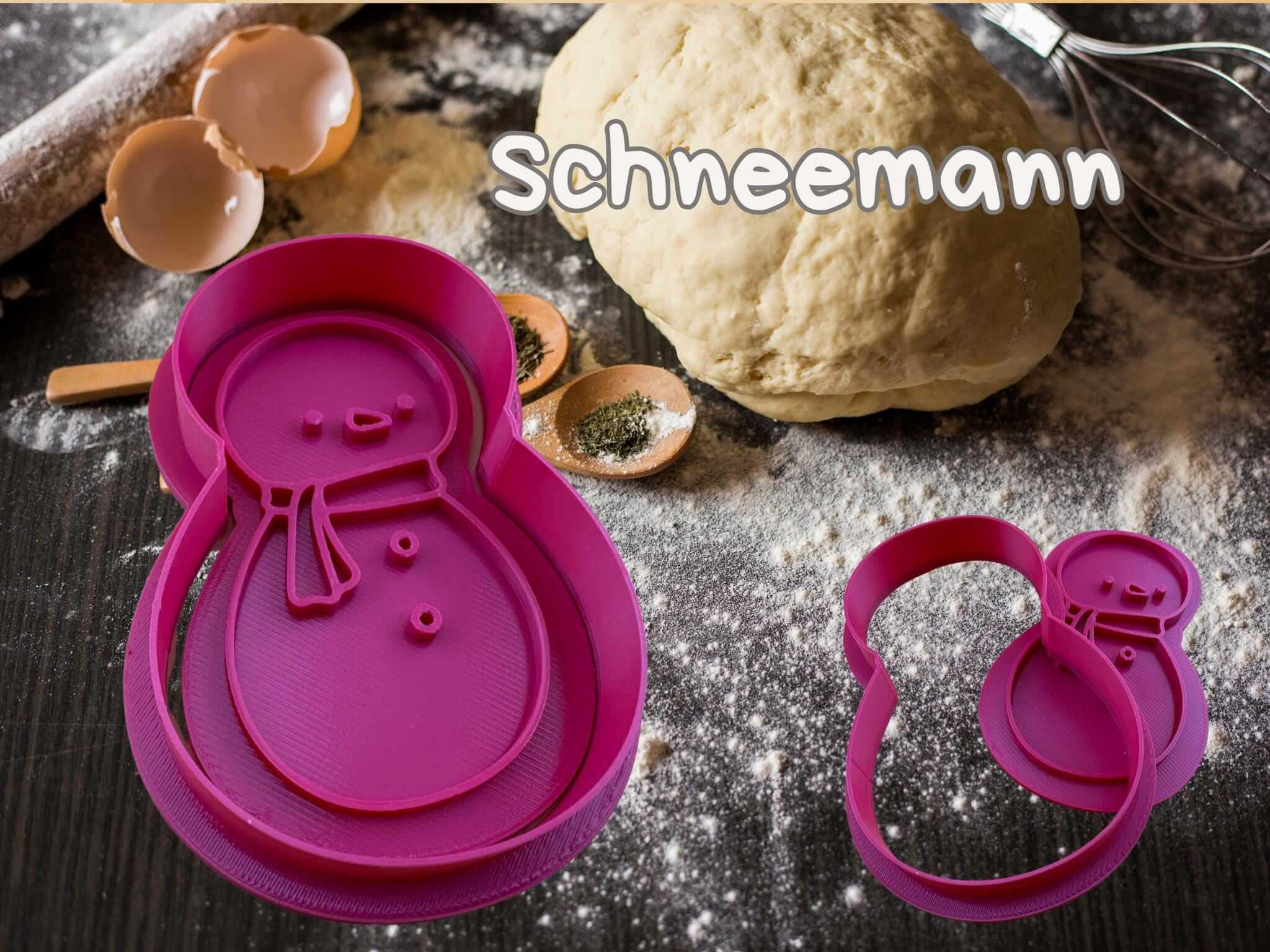 Schneemann Keks-Ausstecher in Pink auf Backtisch mit Teig und Zutaten für festliche Weihnachtsbäckerei.