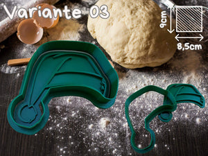 Grüner Keksausstecher in Form einer Vespa neben rohem Teig auf einer bemehlten Arbeitsfläche.