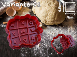 Valentinstag Herz Ausstechformen Keks Ausstecher Set mit Tic-Tac-Toe Design auf einer bemehlten Arbeitsfläche mit Teig.