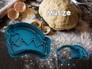 Teal hat-shaped cookie cutter for festive baking, surrounded by dough and kitchen ingredients.