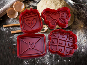 Valentinstag Keks Ausstecher Set: Herz, Liebesbrief, Schleife und Tic-Tac-Toe Formen für romantische Backkunst auf Mehltisch.