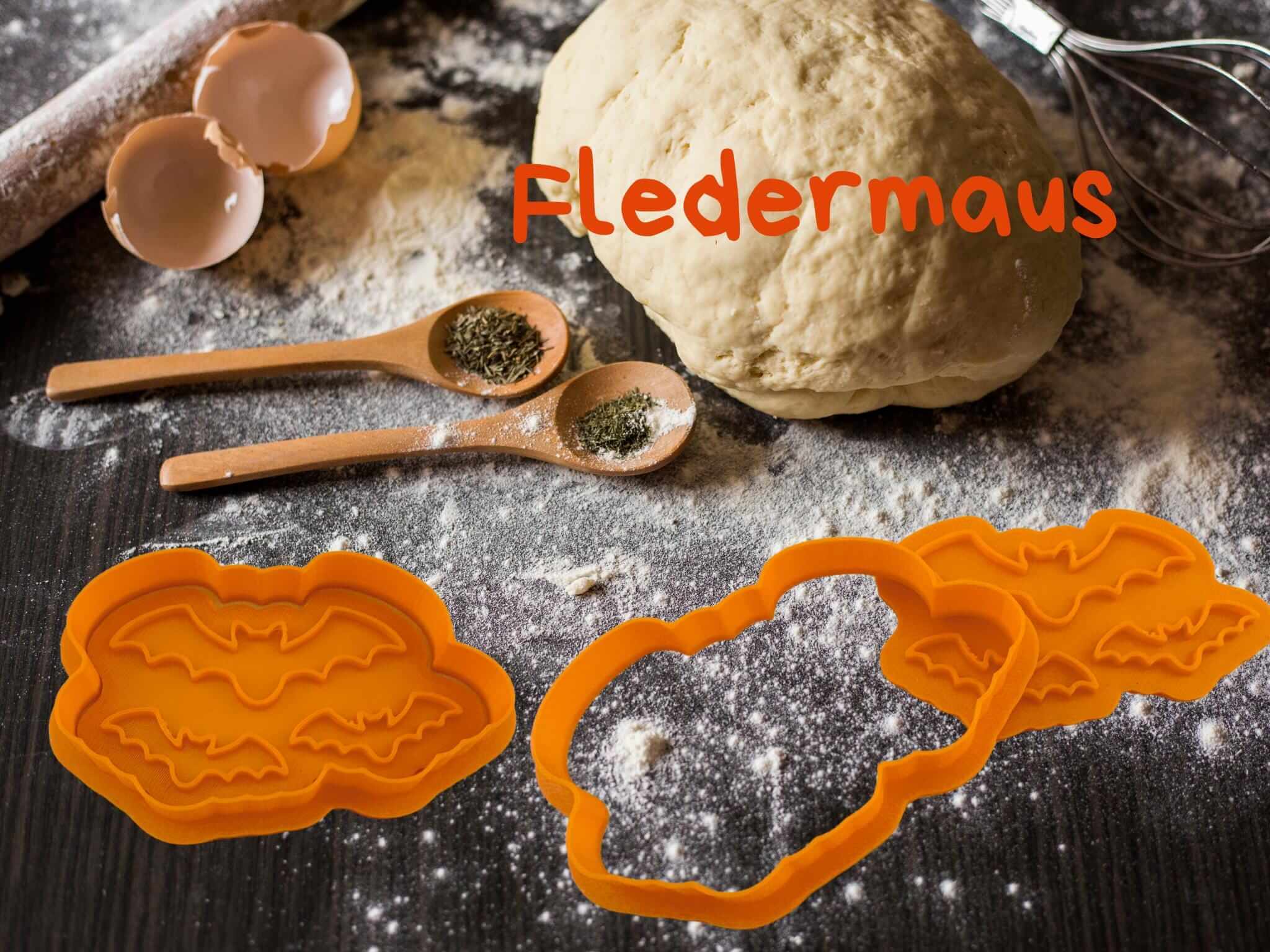 Halloween Fledermaus Keks-Ausstecher auf einem Küchentisch mit Teig und Backutensilien.