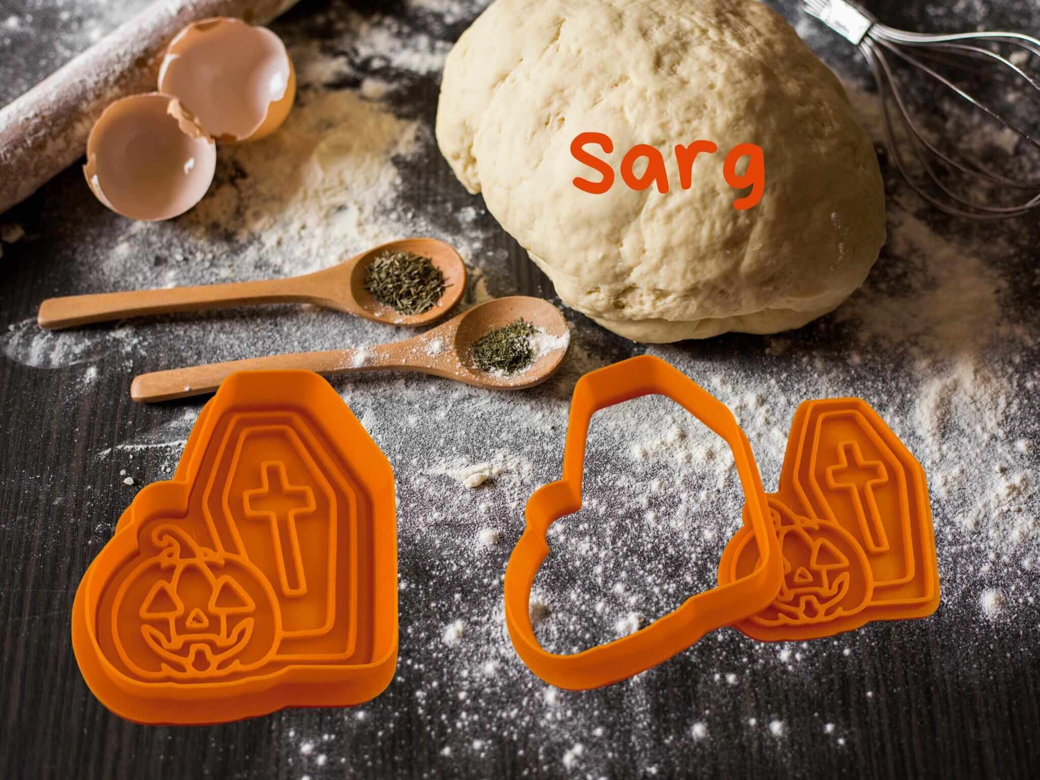 Halloween cookie cutters in coffin shape for spooky baking, with dough and baking tools on a floury surface. Perfect for Halloween fun.