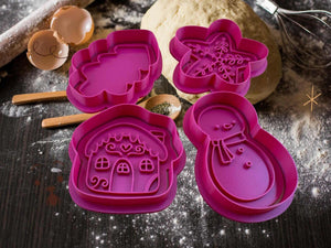 Weihnachtliche Keks-Ausstecher in Form von Schneemann, Lebkuchenhaus, Schneeflocke und Weihnachtsbaum auf einer Backfläche.
