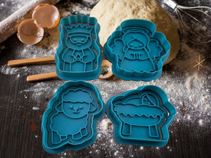 Weihnachtliche Keks-Ausstecher in Form von Engel, König, Schaf und Jesuskind auf einer Backfläche.