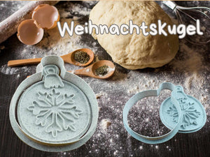 Weihnachtskugel Keks-Ausstecher Set auf einer mehlbestäubten Küchentheke mit Teig und Backutensilien.