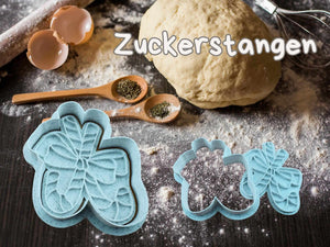 Zuckerstangen Keks-Ausstecher auf einer bemehlten Arbeitsfläche mit Teig und Kuchenzubehör.